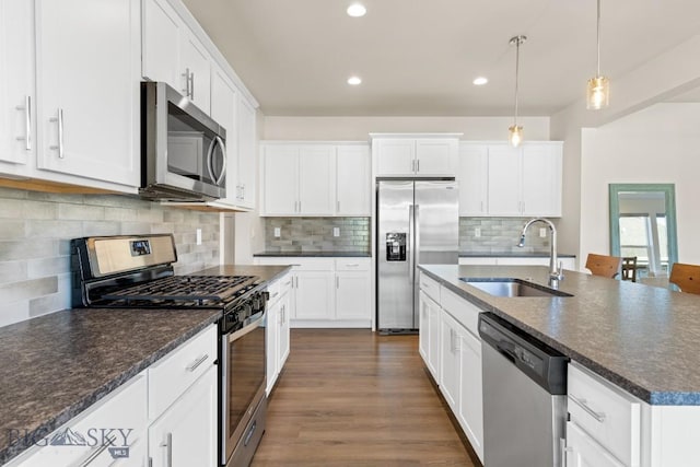 kitchen with decorative backsplash, white cabinets, appliances with stainless steel finishes, and a sink