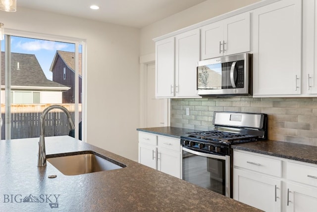 kitchen featuring backsplash, stainless steel appliances, white cabinetry, and a sink