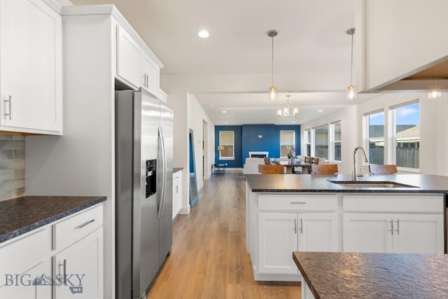 kitchen featuring light wood finished floors, a sink, open floor plan, stainless steel fridge, and a chandelier