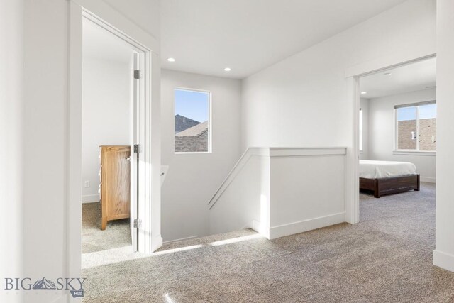 corridor featuring carpet flooring, an upstairs landing, baseboards, and recessed lighting