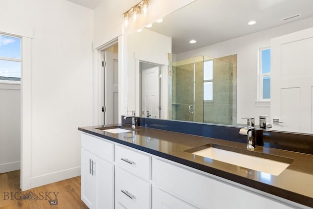 bathroom with double vanity, visible vents, a shower stall, and a sink