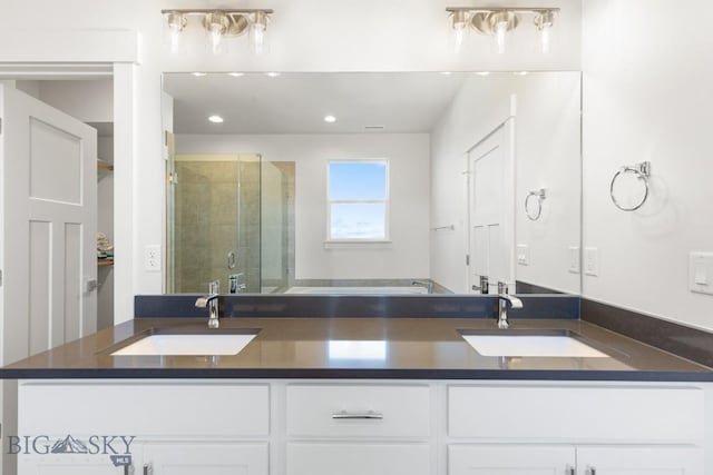 full bath with a sink, double vanity, a stall shower, and recessed lighting