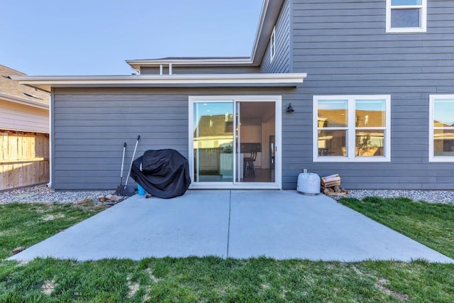 rear view of house with a lawn, a patio, and fence