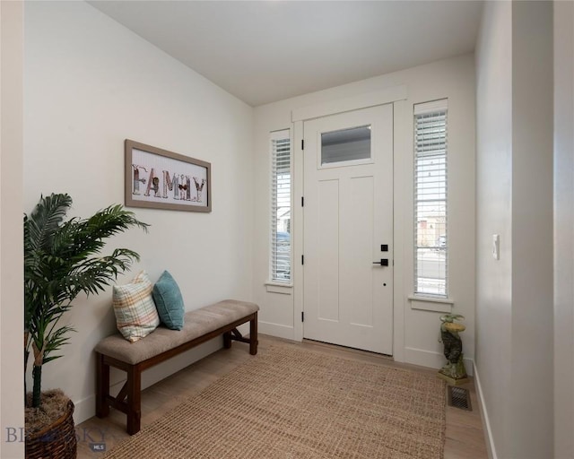 entryway with light wood finished floors, a wealth of natural light, visible vents, and baseboards