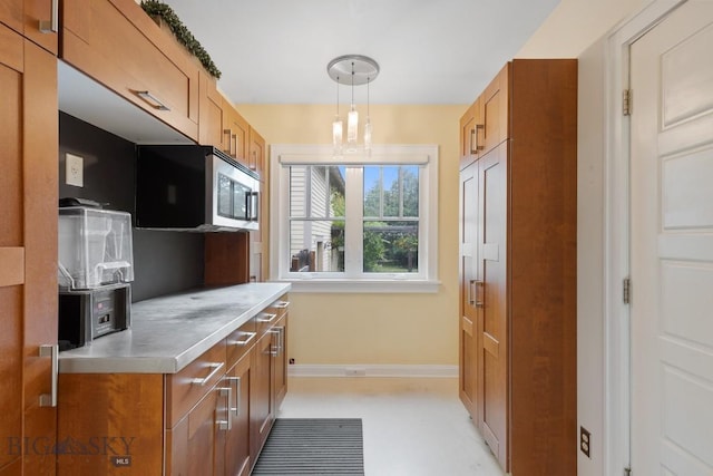 1014 S 6th St, Bozeman, MT 59715 - kitchen featuring pendant lighting, baseboards, brown cabinetry, stainless steel microwave, and stainless steel counters