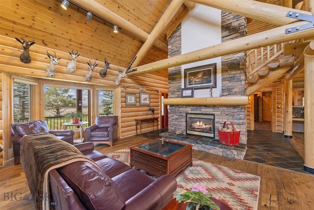 living area featuring a stone fireplace, log walls, track lighting, high vaulted ceiling, and beamed ceiling