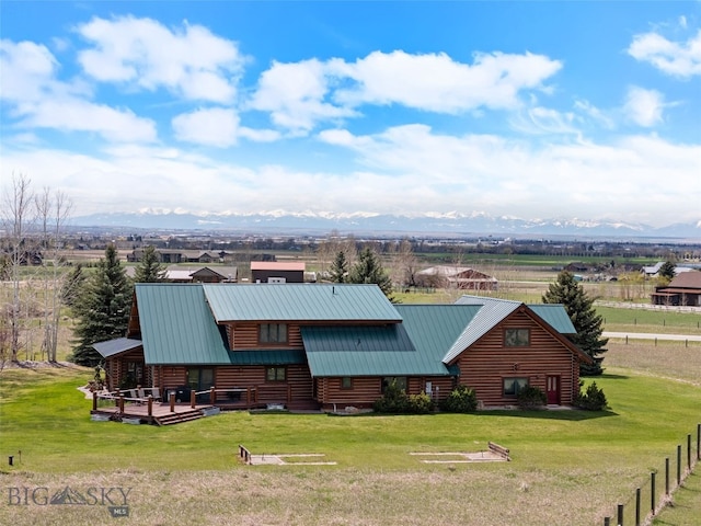 view of front of house with a front yard, metal roof, fence, and log siding