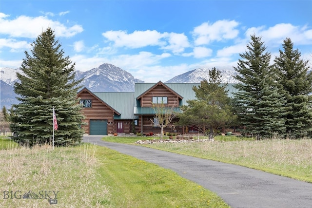 view of front facade featuring aphalt driveway, a mountain view, an attached garage, and log siding