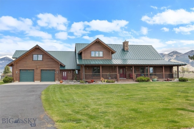 log home featuring a garage, log siding, a chimney, aphalt driveway, and a front yard