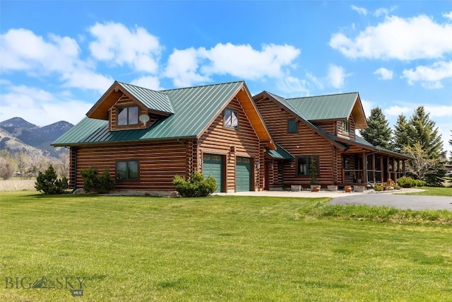 log home featuring a mountain view, log siding, metal roof, aphalt driveway, and a front lawn