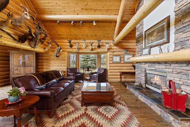 living room with wood ceiling, hardwood / wood-style floors, track lighting, log walls, and a stone fireplace