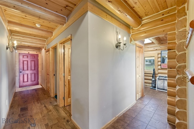 hallway with baseboards, beamed ceiling, log walls, and wooden ceiling