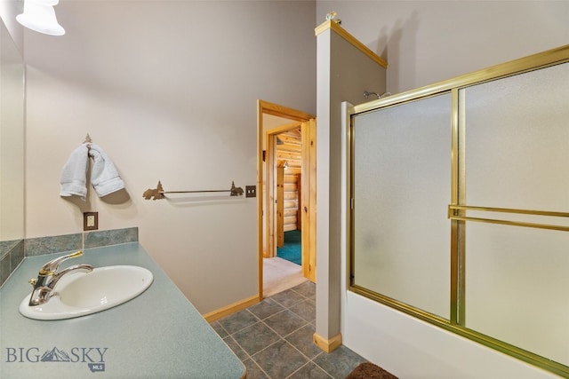 bathroom with shower / bath combination with glass door, tile patterned flooring, baseboards, and a sink