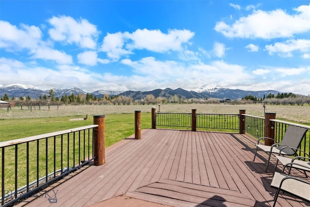 deck featuring a rural view, a mountain view, and a lawn