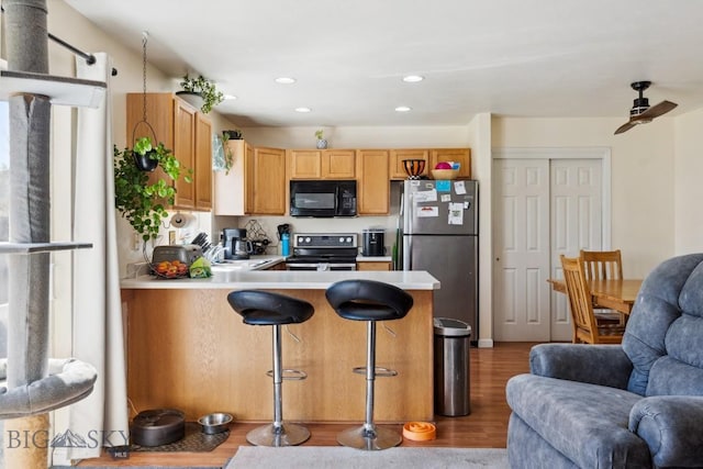 116 Michael Grove Ave, Bozeman, MT 59718 - kitchen with stainless steel appliances, a peninsula, open floor plan, wood finished floors, and light countertops