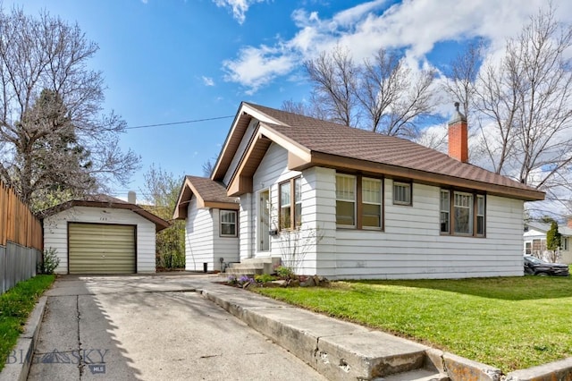 view of front of house with a detached garage, concrete driveway, an outbuilding, a front yard, and a chimney