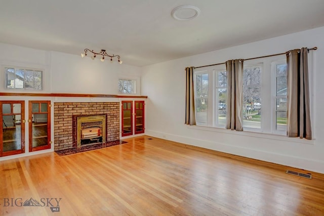 unfurnished living room with baseboards, visible vents, and wood finished floors