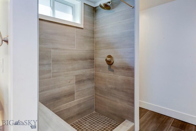 full bathroom featuring baseboards, tiled shower, and wood finished floors