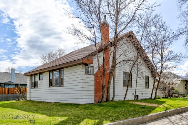view of side of property featuring a yard, a chimney, and fence