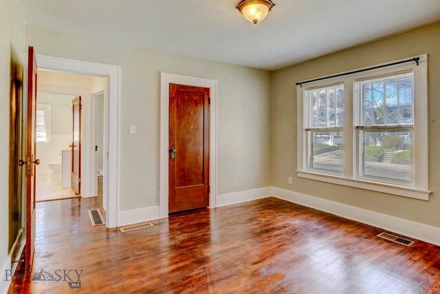 spare room featuring visible vents, wood finished floors, and baseboards
