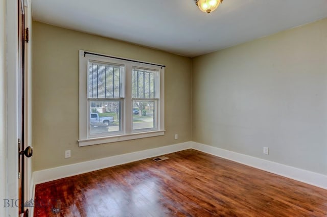 empty room featuring baseboards, visible vents, and wood finished floors