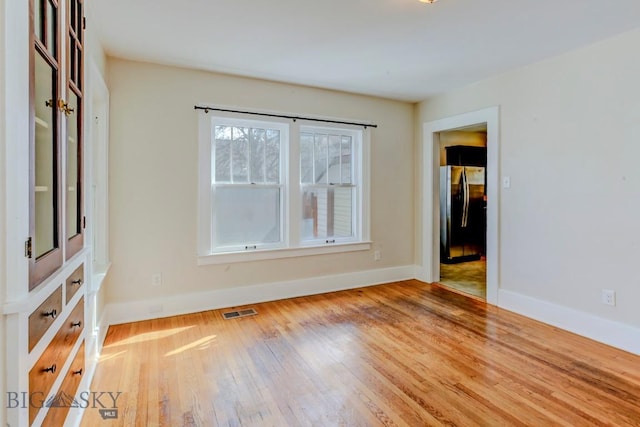 spare room with visible vents, wood finished floors, and baseboards