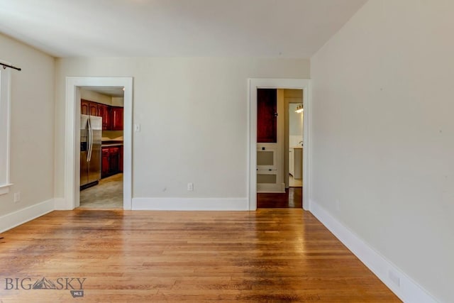 unfurnished room with baseboards and light wood-style floors