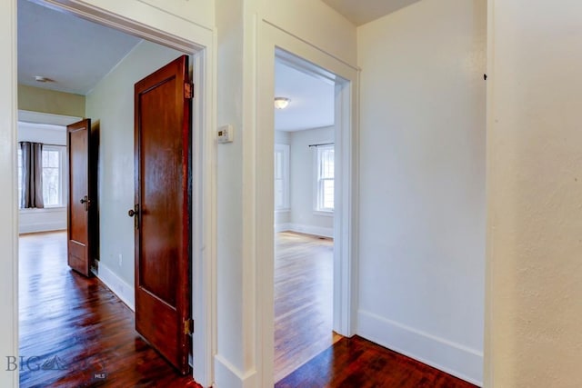 hallway with dark wood-style flooring and baseboards