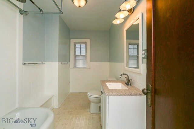 full bathroom featuring tile walls, toilet, a wainscoted wall, vanity, and tile patterned floors