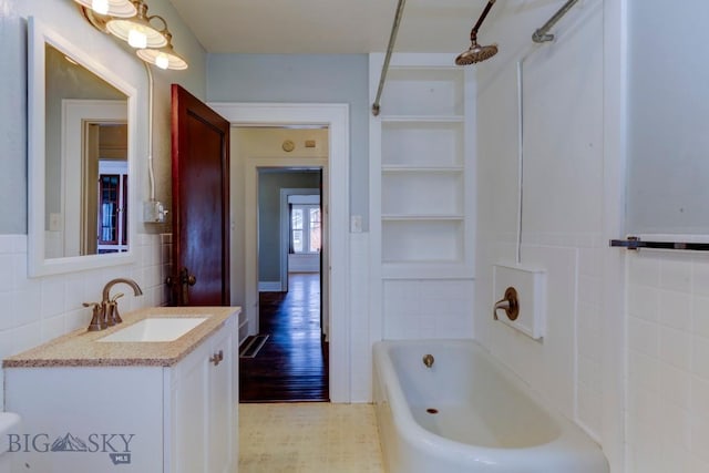 full bath with bathtub / shower combination, tile walls, built in shelves, and vanity