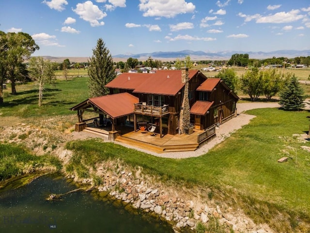 rear view of property featuring a gazebo, metal roof, a wooden deck, a chimney, and a lawn
