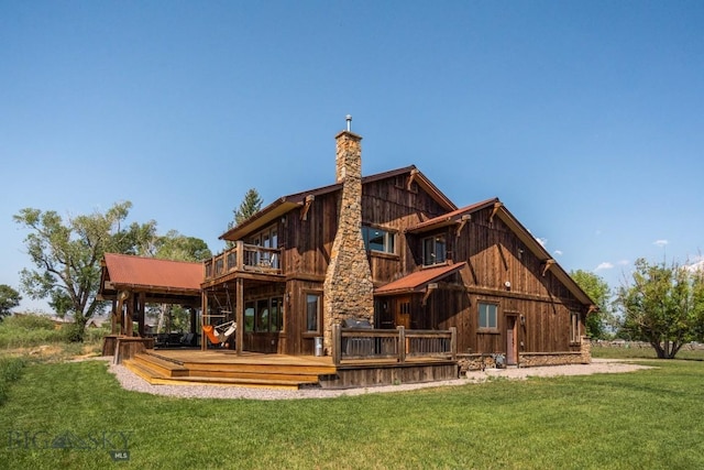 back of property with a chimney, a lawn, a deck, and a balcony