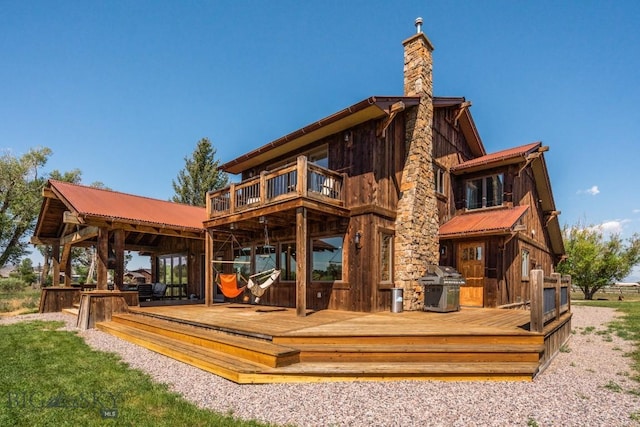rear view of house with a chimney, a deck, a gazebo, and metal roof