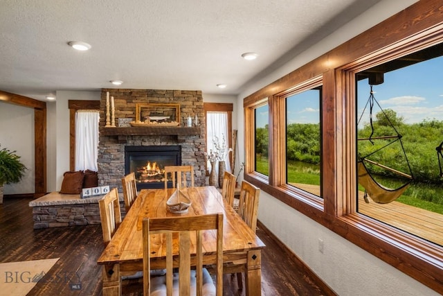 dining room with baseboards, a stone fireplace, and wood finished floors
