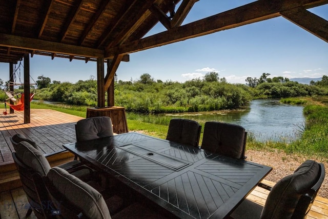 wooden deck featuring a water view and outdoor dining space