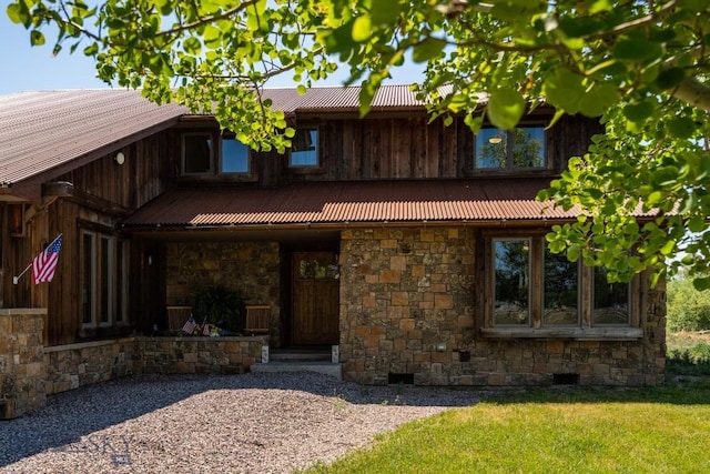 view of front of home featuring stone siding, a front yard, and metal roof