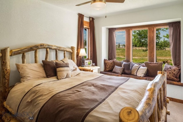 carpeted bedroom with baseboards, ceiling fan, and a textured wall