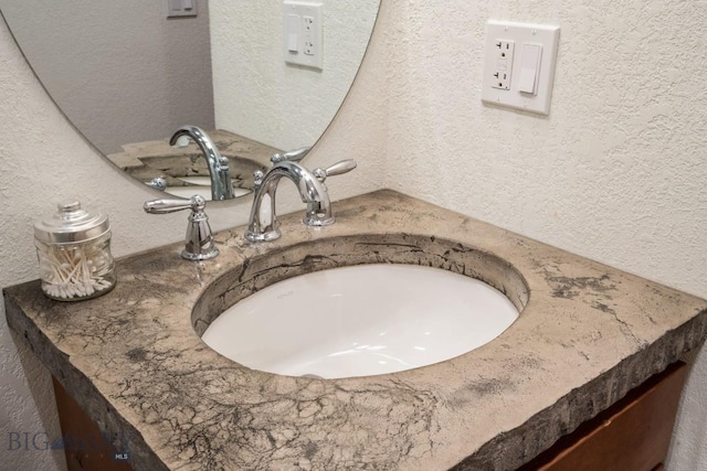 room details featuring vanity and a textured wall