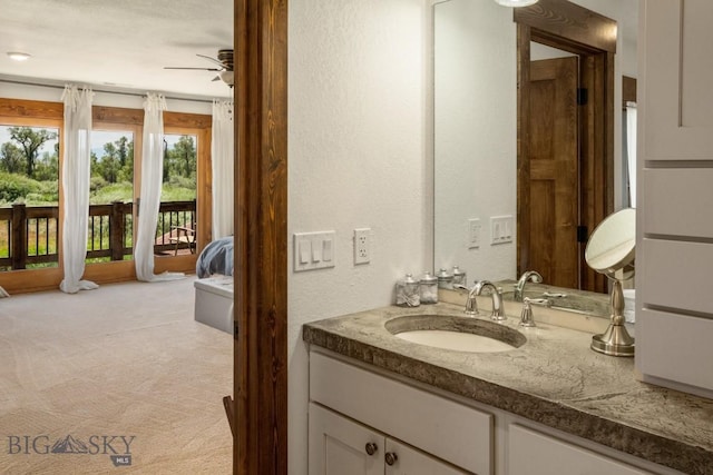 bathroom featuring ceiling fan, a textured wall, and vanity