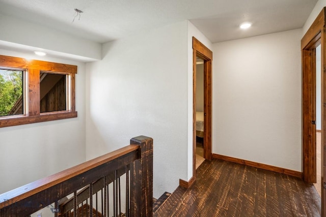 corridor featuring baseboards, dark carpet, an upstairs landing, and recessed lighting