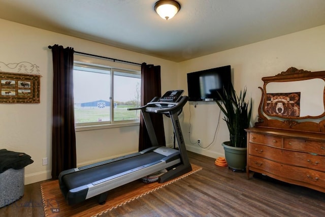 workout room with baseboards and dark wood finished floors