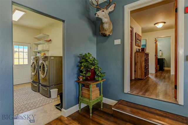laundry room with washing machine and clothes dryer, wood finished floors, baseboards, and laundry area