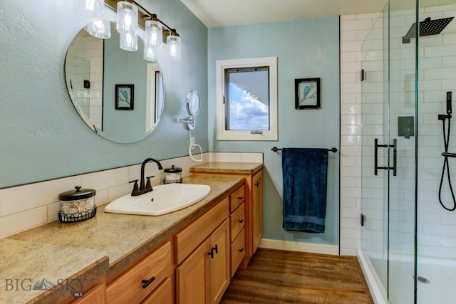 bathroom featuring vanity, decorative backsplash, a shower stall, and wood finished floors