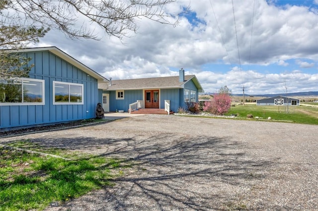 ranch-style house with a chimney, board and batten siding, and driveway