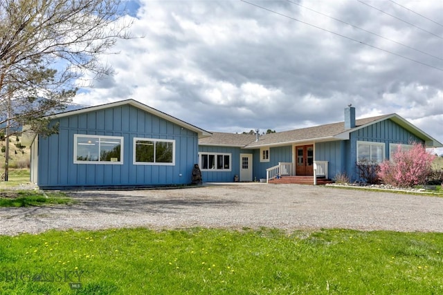 view of front of home with board and batten siding, a chimney, and driveway