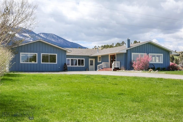 view of front of house with a front lawn, a mountain view, and a chimney