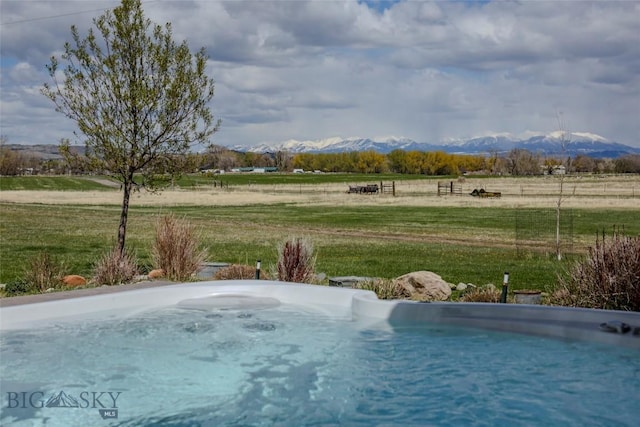 view of swimming pool featuring a lawn, a rural view, and a mountain view