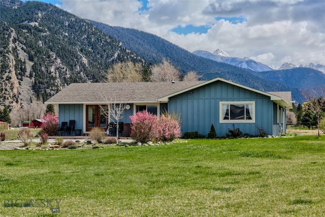view of front facade featuring a front lawn, board and batten siding, a porch, and a mountain view
