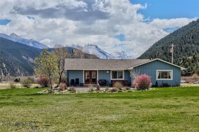 back of house with a lawn, french doors, and a mountain view
