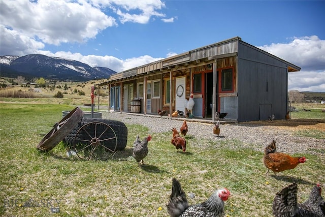 back of house with a lawn and a mountain view